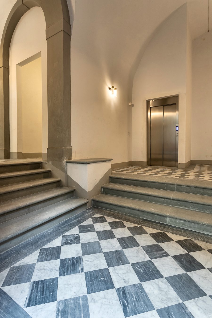 Palazzo Pasqui: entrance hall with stone arches and a checkerboard marble floor